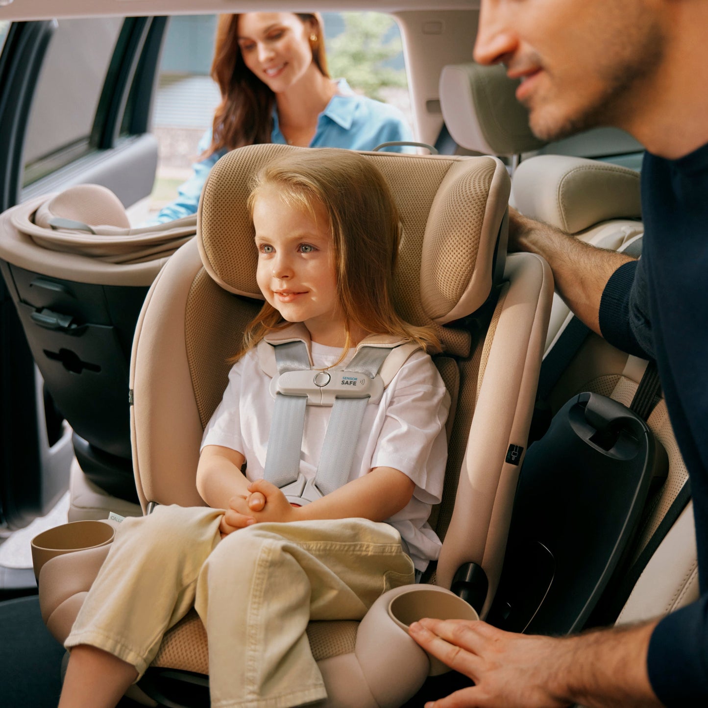 Child in a callisto car seat being helped by an adult in a vehicle.