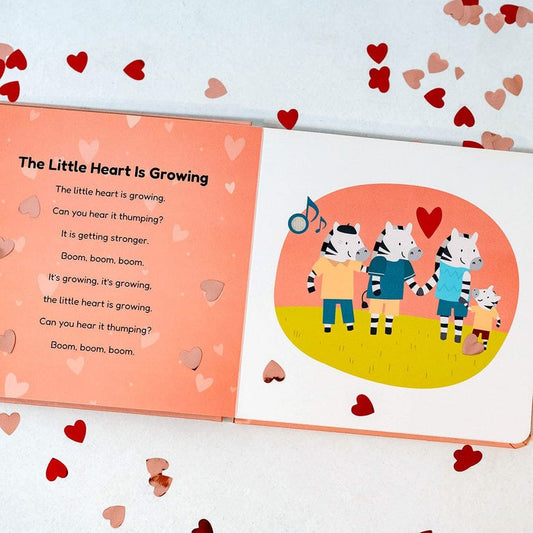 An open children's book spread on a white background with scattered red and pink hearts. The left page has the title 'The Little Heart Is Growing' and a poem on a peach background.