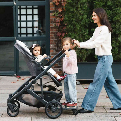 Woman pushing a stroller with two children outdoors.