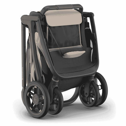 
A compact, folded beige and grey baby stroller standing upright on a white background.