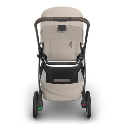 
Rear view of a beige baby stroller with a grey frame, handle, and storage basket, isolated on a white background.