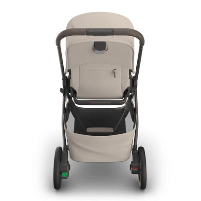 
Rear view of a beige baby stroller with a grey frame, handle, and storage basket, isolated on a white background.