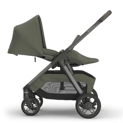 
Rear view of an olive green baby stroller with a grey frame, handle, and storage basket, isolated on a white background.