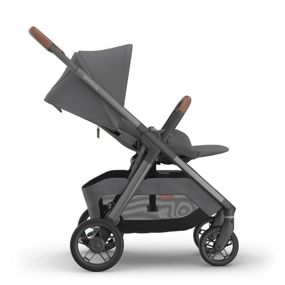 
Side profile of a reclined grey forward-facing baby stroller with brown leather handle grips, isolated on a white background.