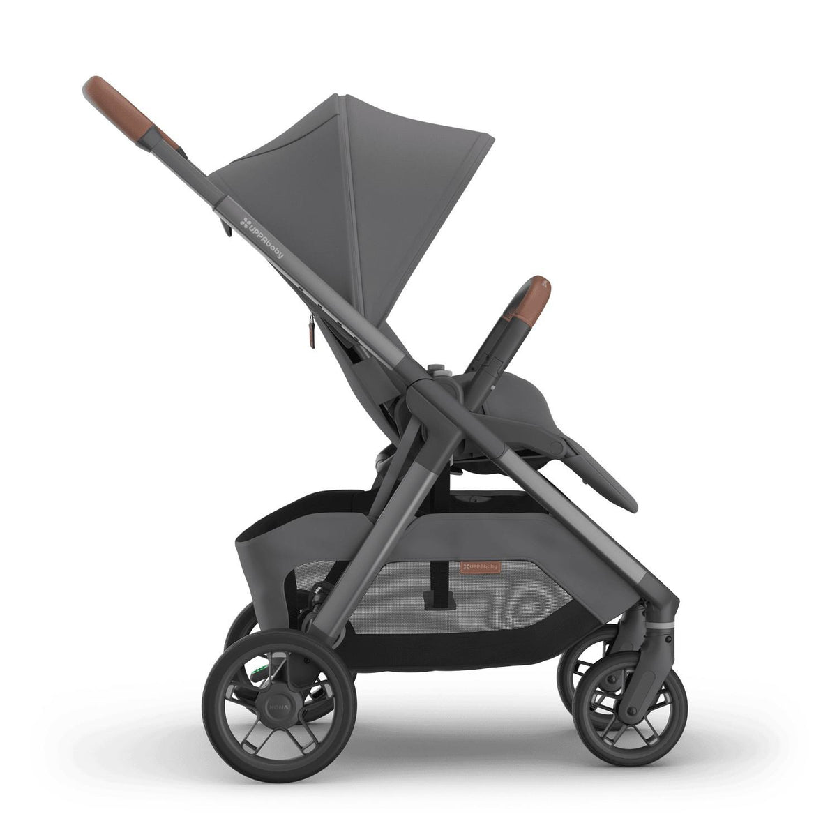 
Side profile of a grey forward-facing baby stroller with an extended sun canopy and brown leather handle grips, isolated on a white background.