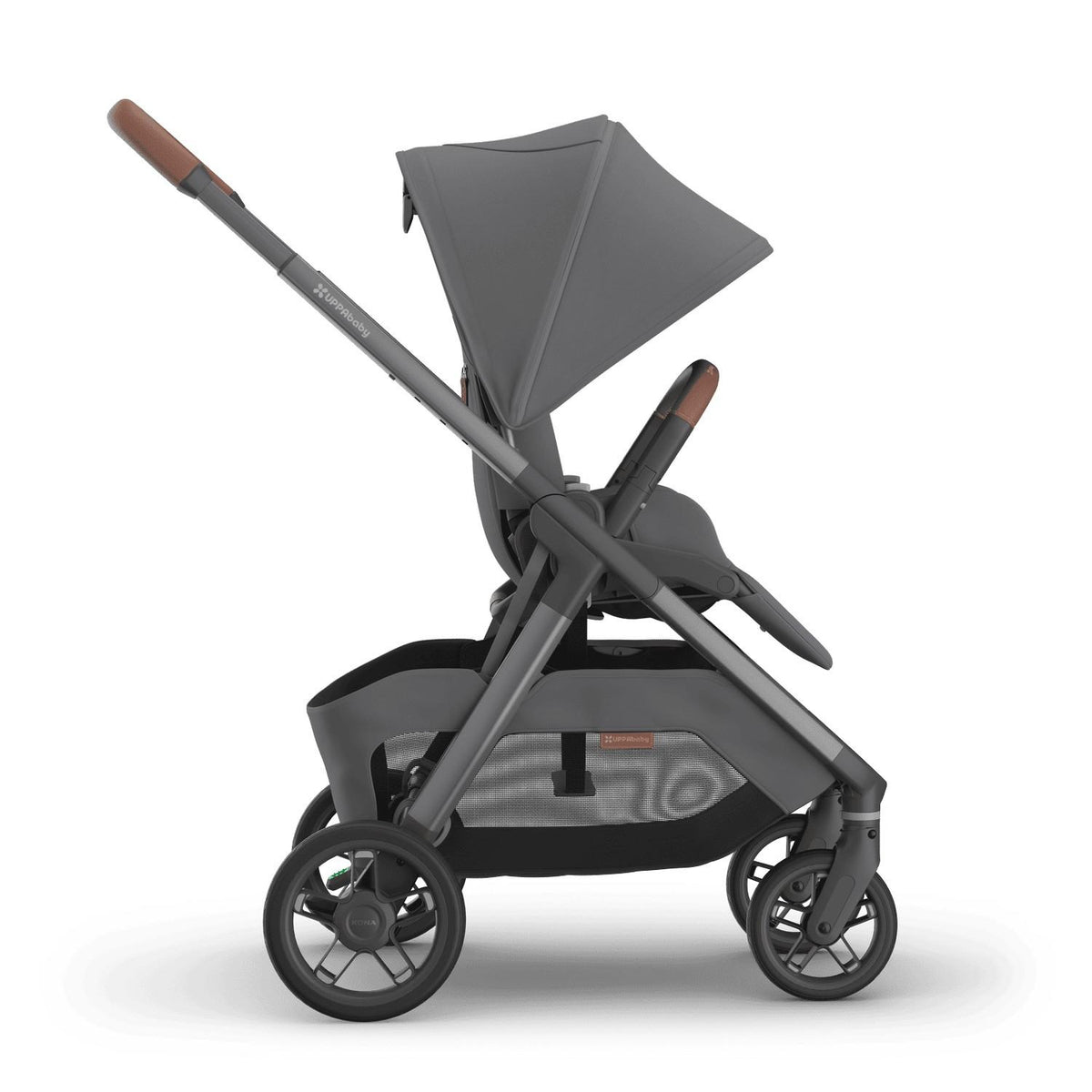 
Side profile of a grey parent-facing baby stroller with an extended sun canopy and brown leather handle grips, isolated on a white background.