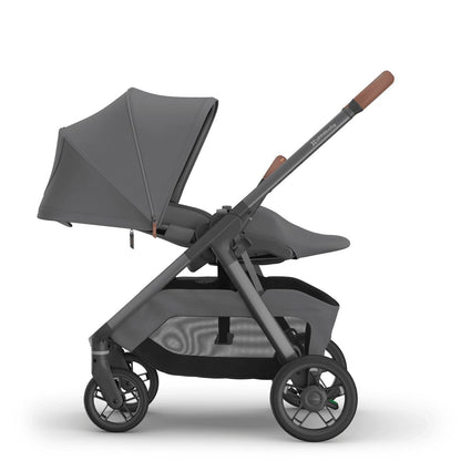 
Side profile of a reclined grey parent-facing baby stroller with an extended sun canopy and brown leather handle grips, isolated on a white background.