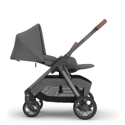 
Side profile of a reclined grey parent-facing baby stroller with brown leather handle grips, isolated on a white background.