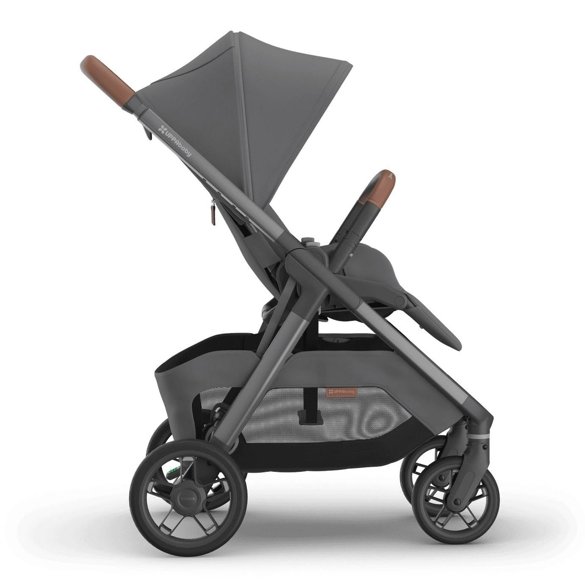
Side profile of an upright grey forward-facing baby stroller with an extended sun canopy and brown leather handle grips, isolated on a white background.