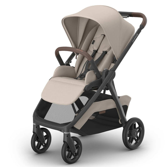 A modern stroller with a light beige fabric canopy and seat, a dark gray frame, and brown leather-look handlebar grips, shown on a clean white background.