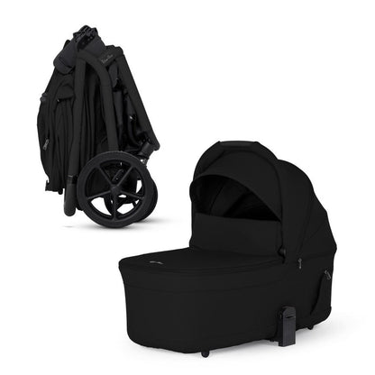 A compactly folded all-black stroller frame standing next to its matching standalone bassinet.