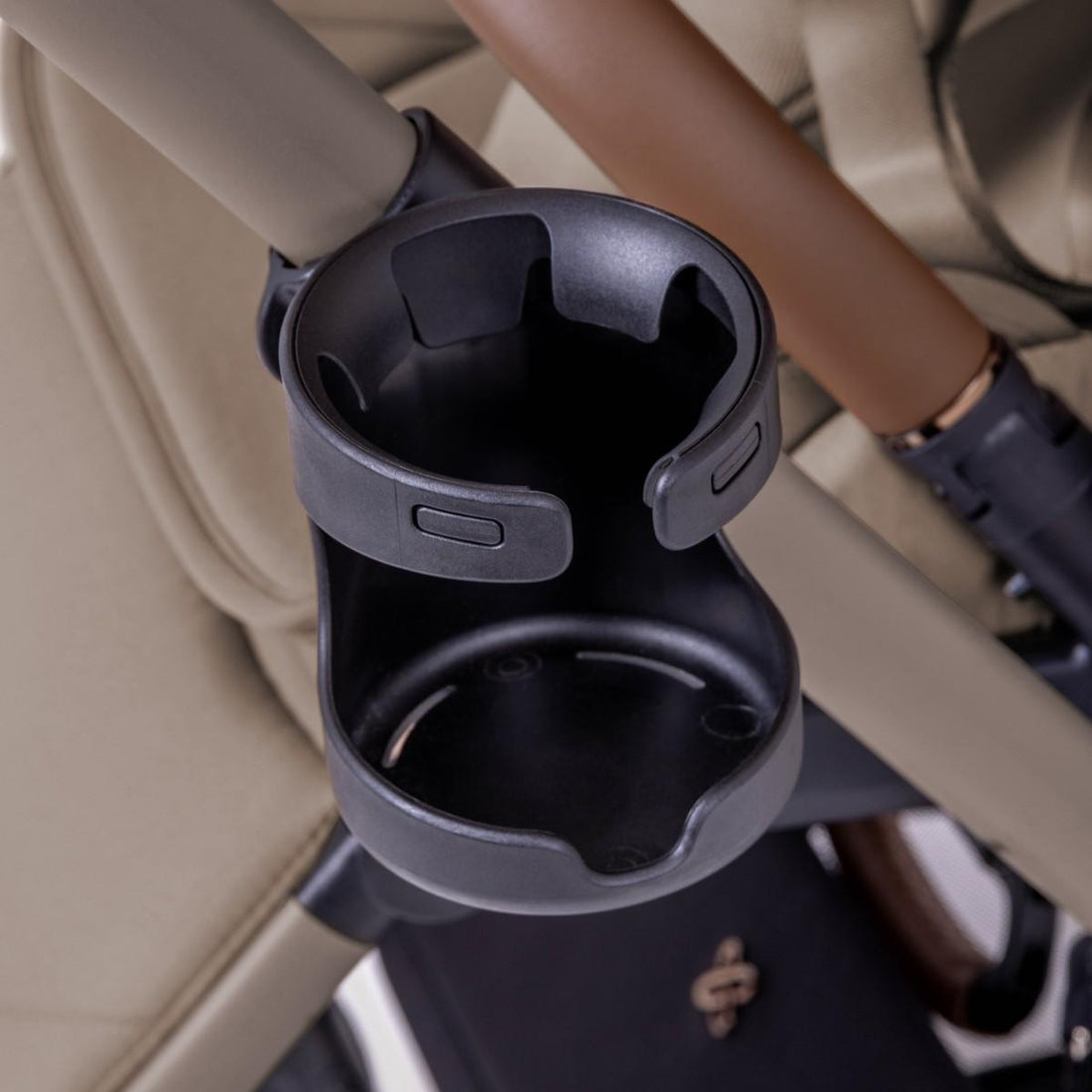 Close-up view of a black plastic cup holder attached to a stroller frame.