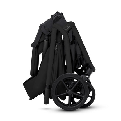 A side view of a compactly folded all-black stroller standing upright.
