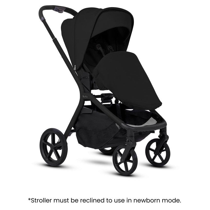 An all-black stroller fitted with a newborn apron, accompanied by informational text overlay at the bottom.
