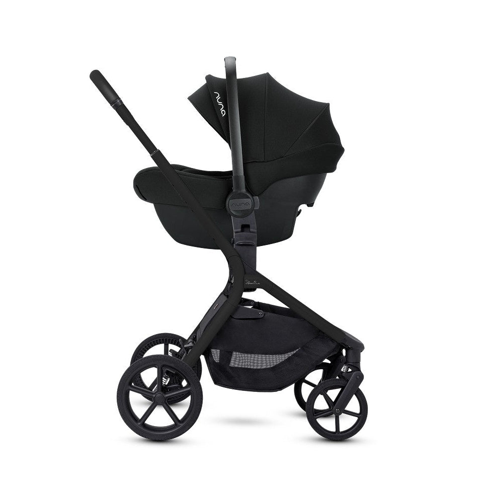 A side view of an all-black stroller frame configured with an attached infant car seat.