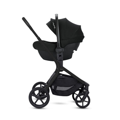 A side view of an all-black stroller frame configured with an attached infant car seat.