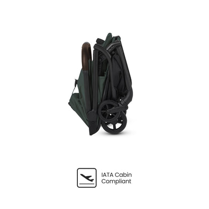 Dark green travel stroller shown compactly folded from a side profile, displayed above an "IATA Cabin Compliant" logo.