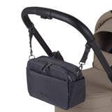 A black fabric stroller organizer bag hanging from a black leather handlebar by adjustable straps.