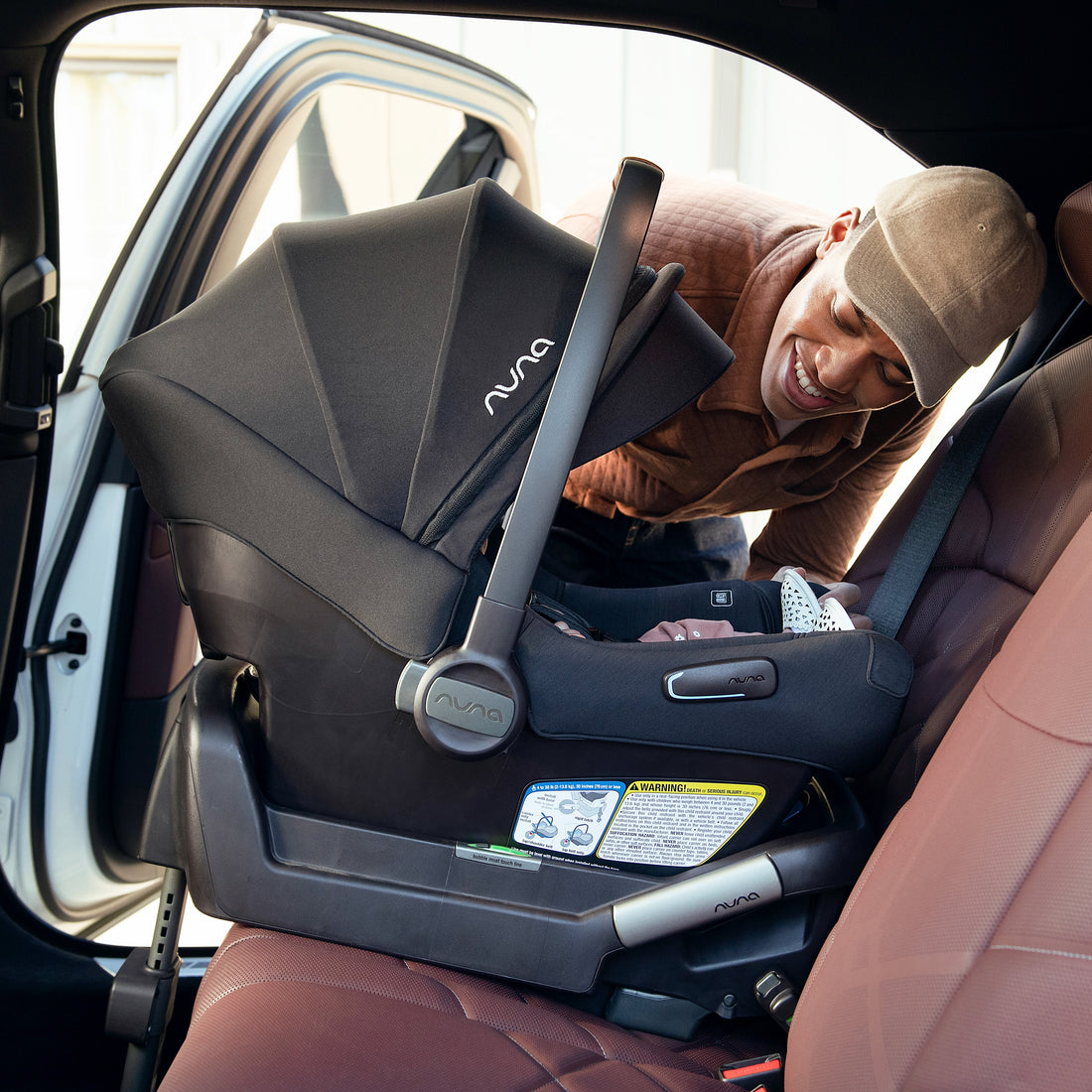 
Nuna PIPA Aire infant car seat in Caviar shown installed in the car with the original series base lifestyle with dad and baby