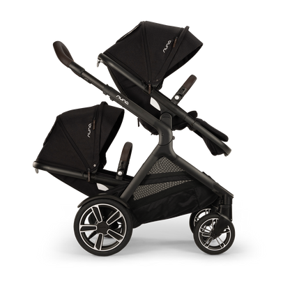 
Side profile of a double black stroller configured with two facing seats and extended canopies, isolated on a transparent background.