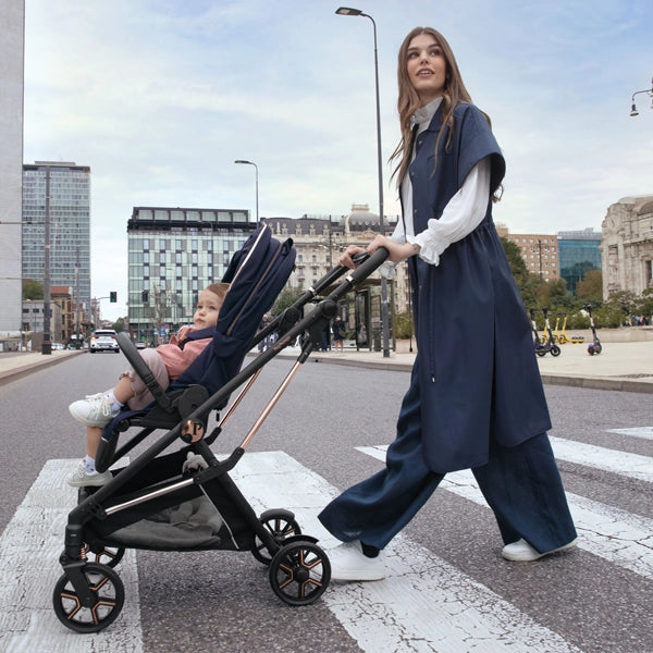 Peg Perego Vivace Lightweight Stroller in Blue Shine with Forward Facing Seat Crossing a City Sidewalk