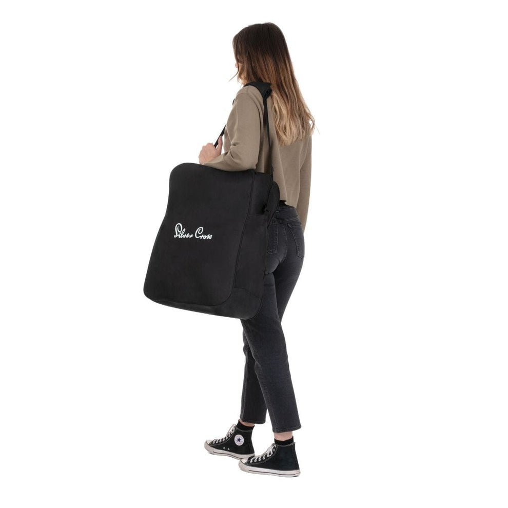 A woman carrying a black stroller travel bag over her shoulder.