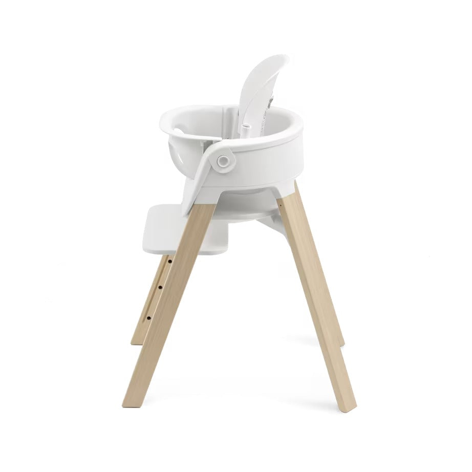 
A modern high chair with a white plastic seat and a natural light wood frame, shown from a side profile view against a solid white background.