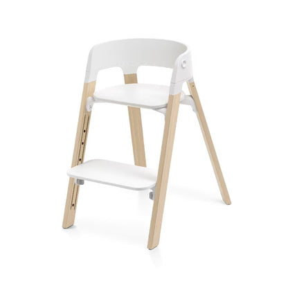 
A modern two-step children's chair with a white molded plastic seat, backrest, and footrest, supported by four adjustable light natural wood legs, shown on a clean white background.
