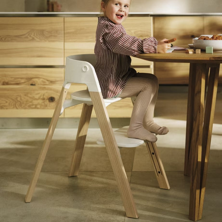 
Child sitting on a modern wooden chair in a kitchen