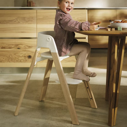 
Child sitting on a modern wooden chair in a kitchen