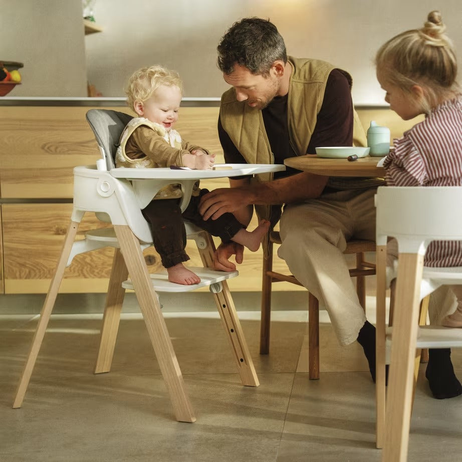 
Man with two children at a dining table, one in a high chair.