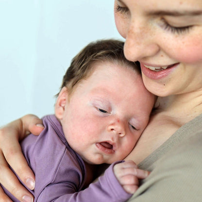 Woman holding a baby close to her face with a light blue background