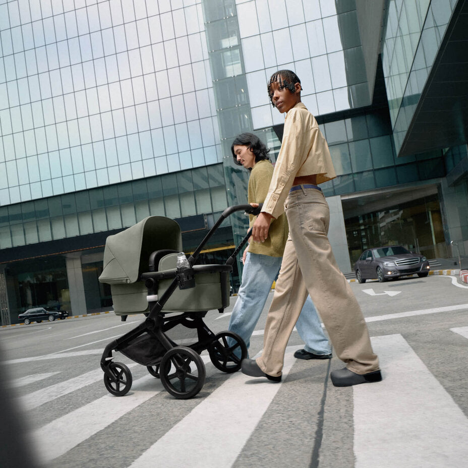 Two adults walking through a city center with a Bugaboo stroller.
