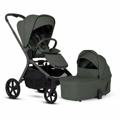 A stroller and bassinet travel system in a muted sage green color, shown on a clean white background. The stroller features a dark gray frame and black wheels, with a matching green footmuff and a separate bassinet placed beside it.