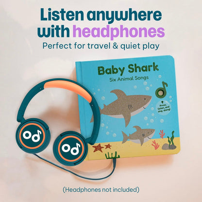 
A children's hardcover book titled 'Baby Shark' with illustrated shark artwork on a blue cover, shown next to teal and orange over-ear headphones on a light background. Large text at the top reads 'Listen anywhere with headphones' and smaller text says 'Perfect for travel & quiet play.