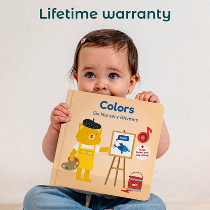 
A baby girl holds a colorful children's board book titled 'Colors: Six Nursery Rhymes' against a light beige background. The top of the image features the text 'Lifetime warranty' in dark teal.