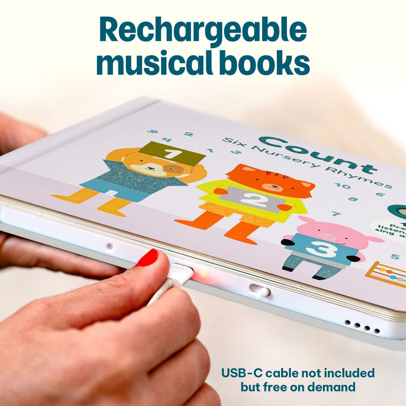 
Hands plugging a charging cable into a rechargeable "Count" children's musical book.