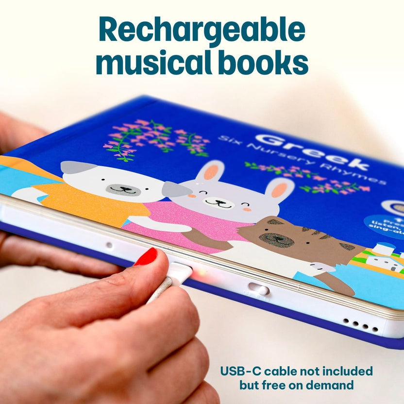 
Hands plugging a charging cable into a rechargeable blue "Greek Nursery Rhymes" children's musical book.