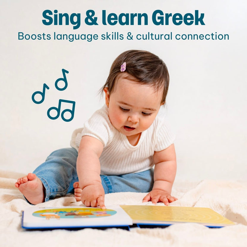 
A baby sitting on a blanket pressing a sound button on an open Greek interactive book.