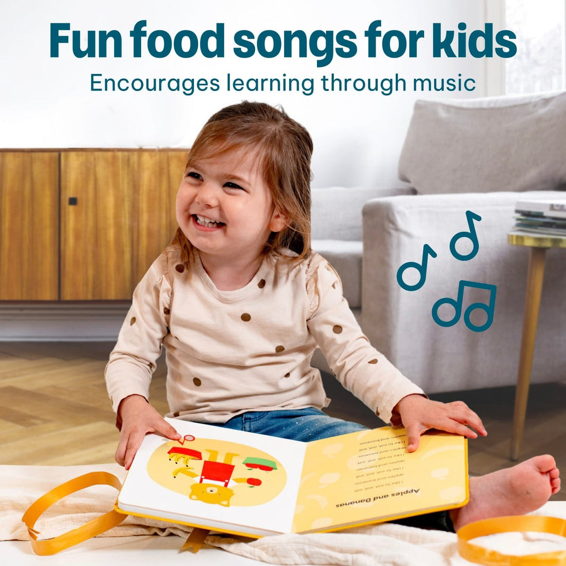 
A young child sitting on a blanket in a living room, holding an open children's picture book with a yellow loop strap. The scene includes marketing text at the top about fun food songs for kids and music icons on the right.