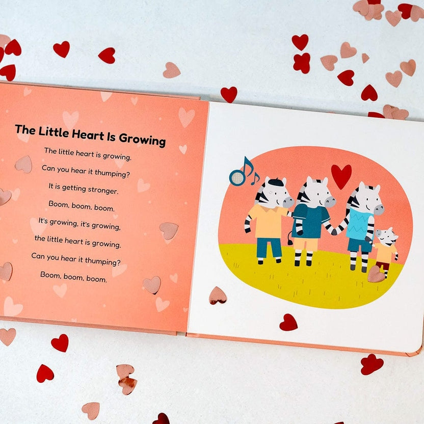 
An open children's book spread on a white background with scattered red and pink hearts. The left page has the title 'The Little Heart Is Growing' and a poem on a peach background.