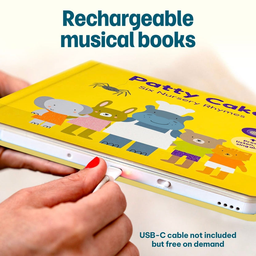 
Hands plugging a charging cable into a rechargeable "Patty Cake" children's musical book.