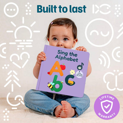 
A baby sitting on a light floor holding a purple children's alphabet book titled 'Sing the Alphabet.' The background is white with simple white line icons, and the image includes the text 'Built to last' and a purple 'Lifetime Warranty' badge.