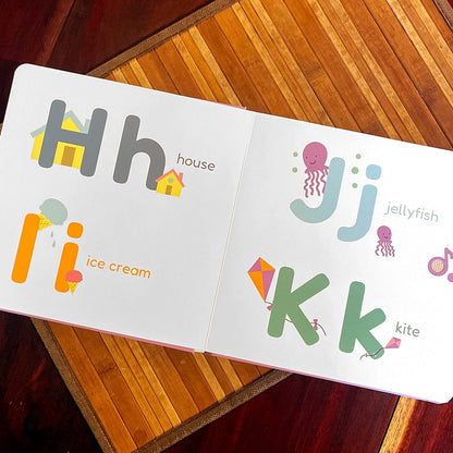 
Open book showing alphabet letters H, J, I, K on a wooden surface