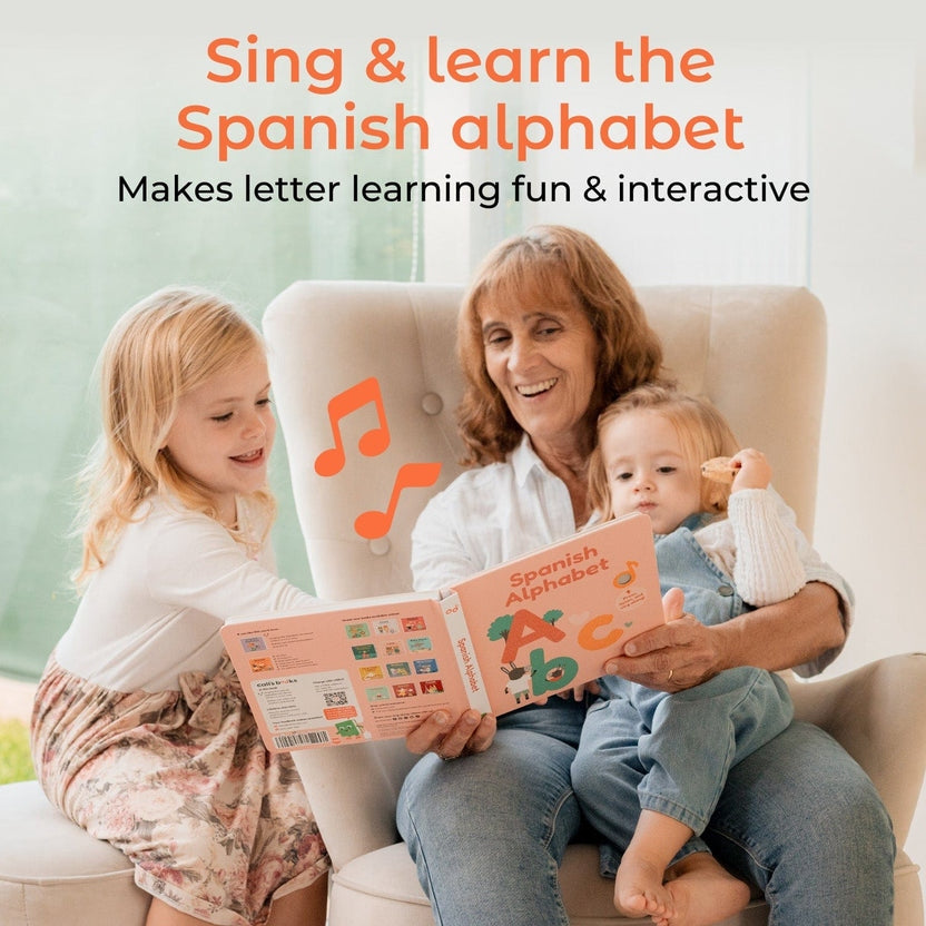 
Woman and two children reading a book titled 'Spanish Alphabet' with music notes on a couch.