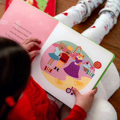 
A child pressing a musical button on an open "Nutcracker" board book.