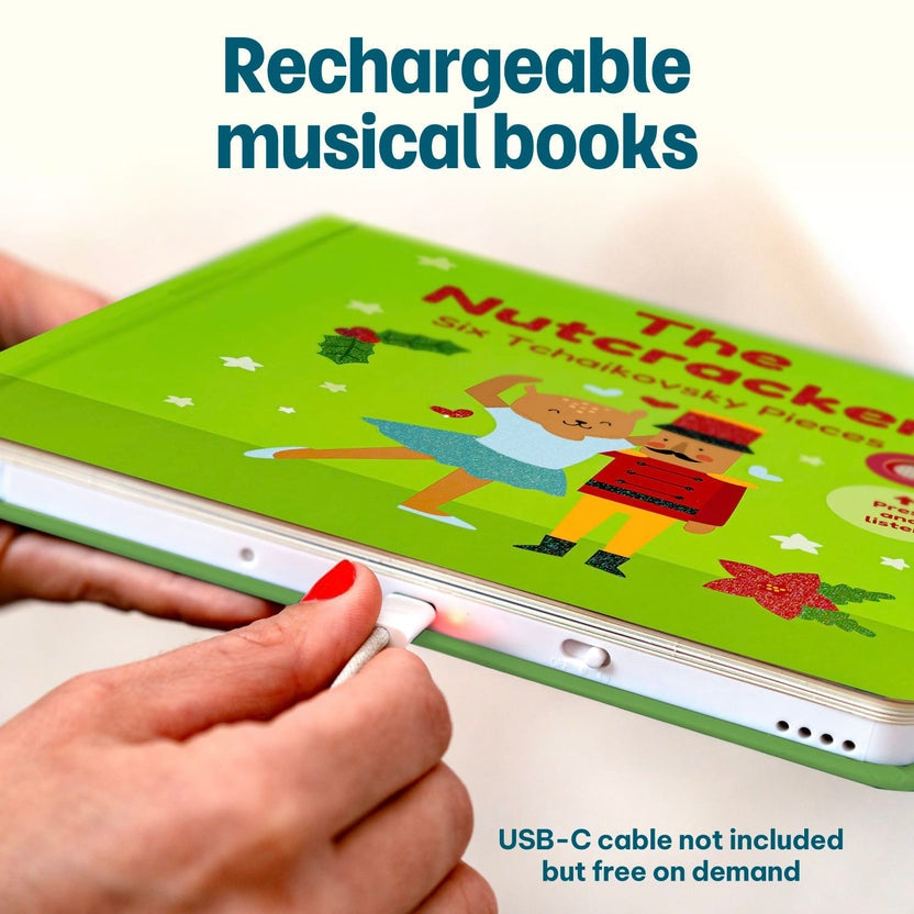
Hands plugging a charging cable into a rechargeable green "The Nutcracker" children's musical book.