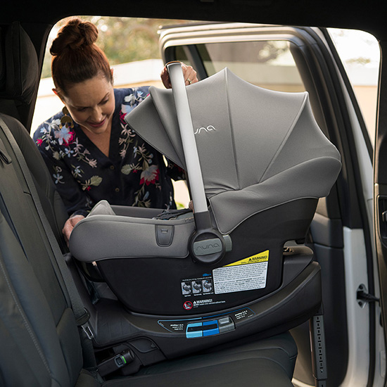 a woman installing the Nuna Pipa RX and Relx Base car seat